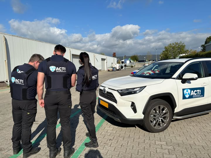 3 leden van het ACT team in zwarte kleding staan bij witte auto van het ACT team